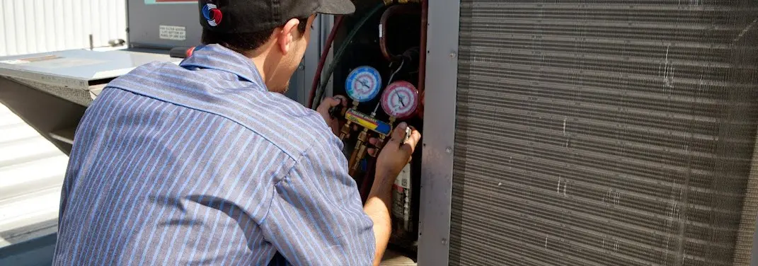 HVAC technician servicing a condenser unit in McKeesport